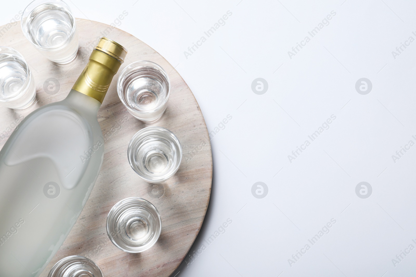 Photo of Bottle of vodka and shot glasses on white background, top view. Space for text