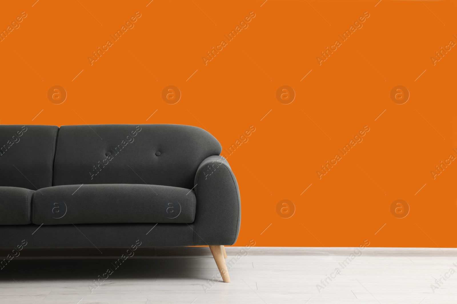 Photo of Stylish grey sofa near orange wall indoors, space for text. Interior design