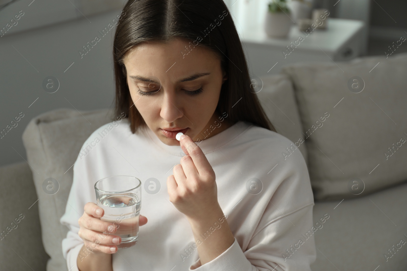 Photo of Young woman taking abortion pill at home