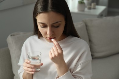 Photo of Young woman taking abortion pill at home