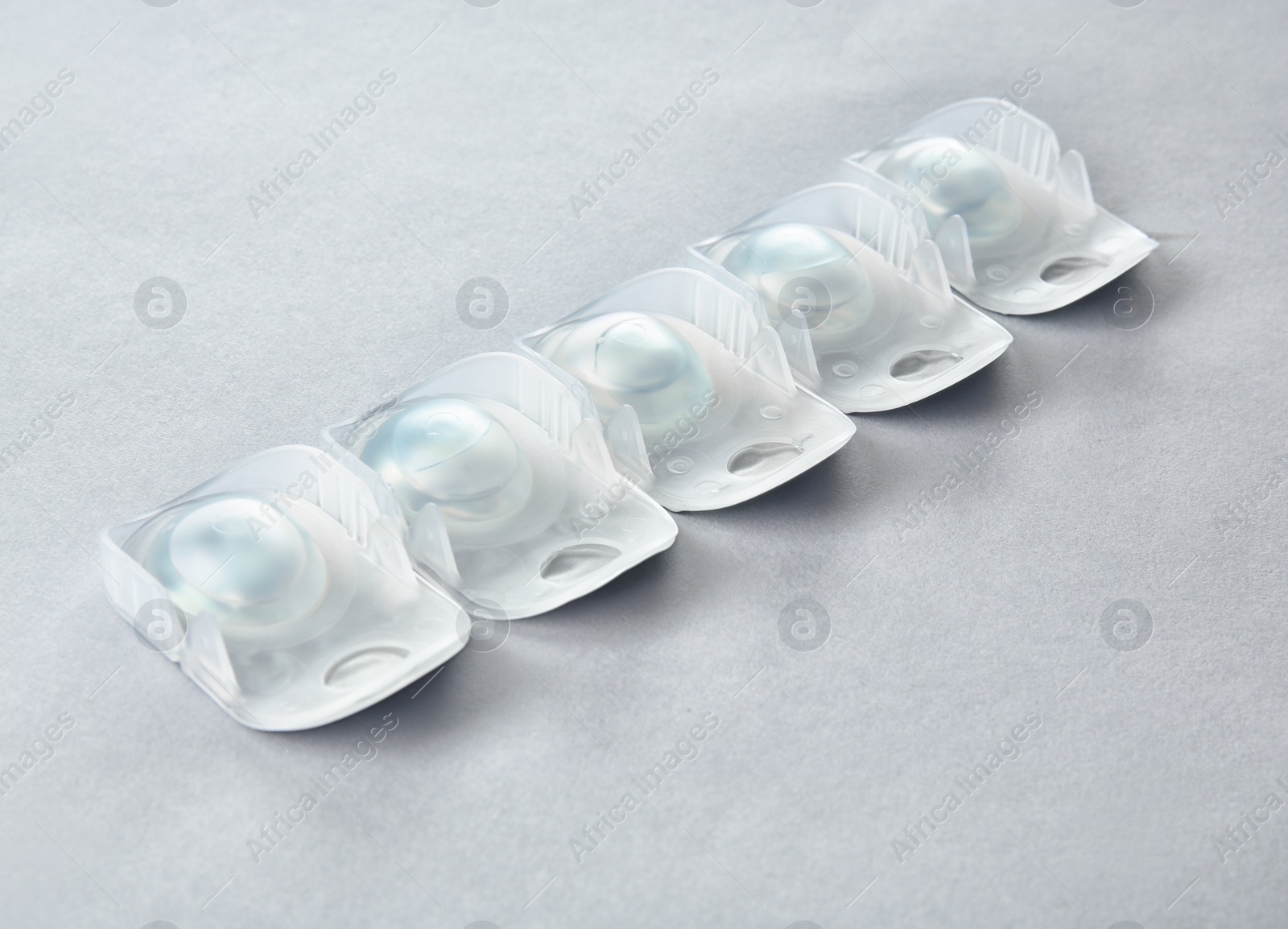Photo of Packages with contact lenses on light background