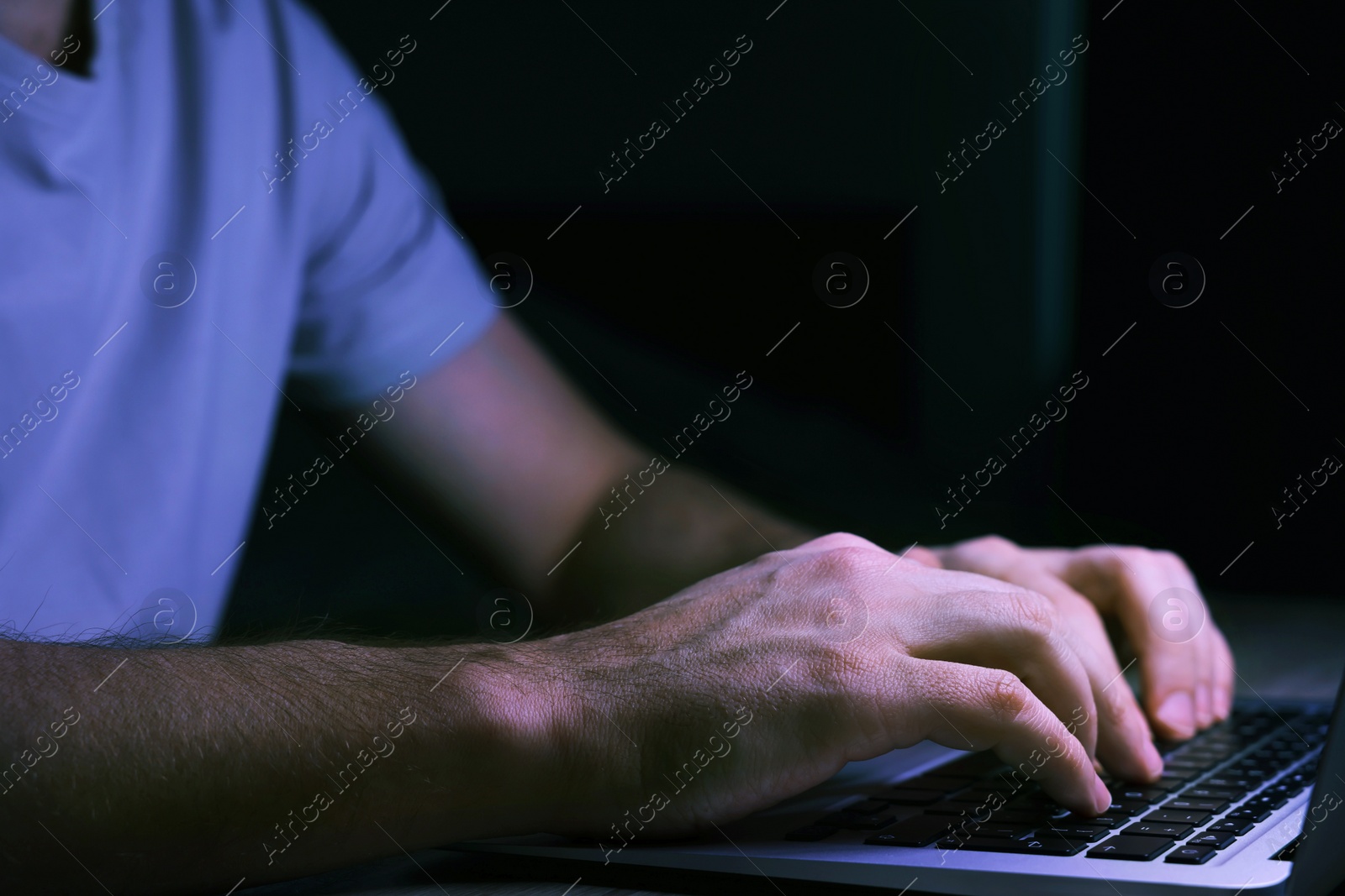 Photo of Man using computer at night, closeup. Internet addiction