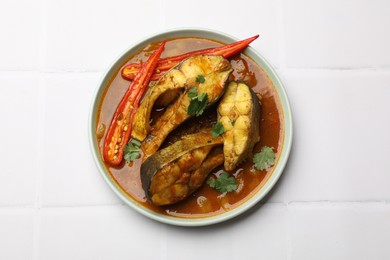 Photo of Tasty fish curry on white tiled table, top view. Indian cuisine