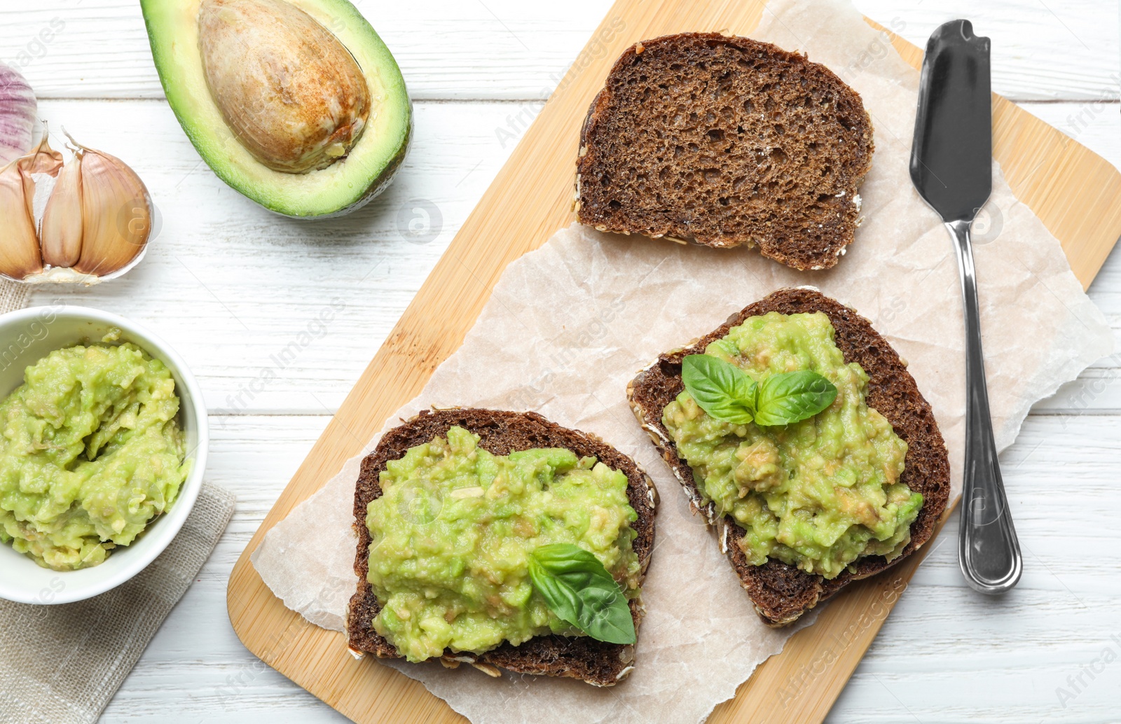 Photo of Flat lay composition with tasty avocado sandwiches on white wooden table