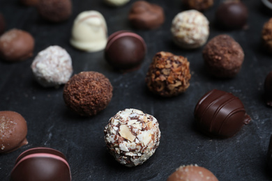 Photo of Different delicious chocolate candies on black table, closeup