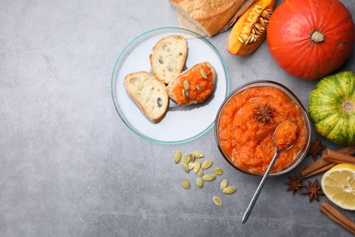 Photo of Delicious pumpkin jam and ingredients on grey table, flat lay. Space for text