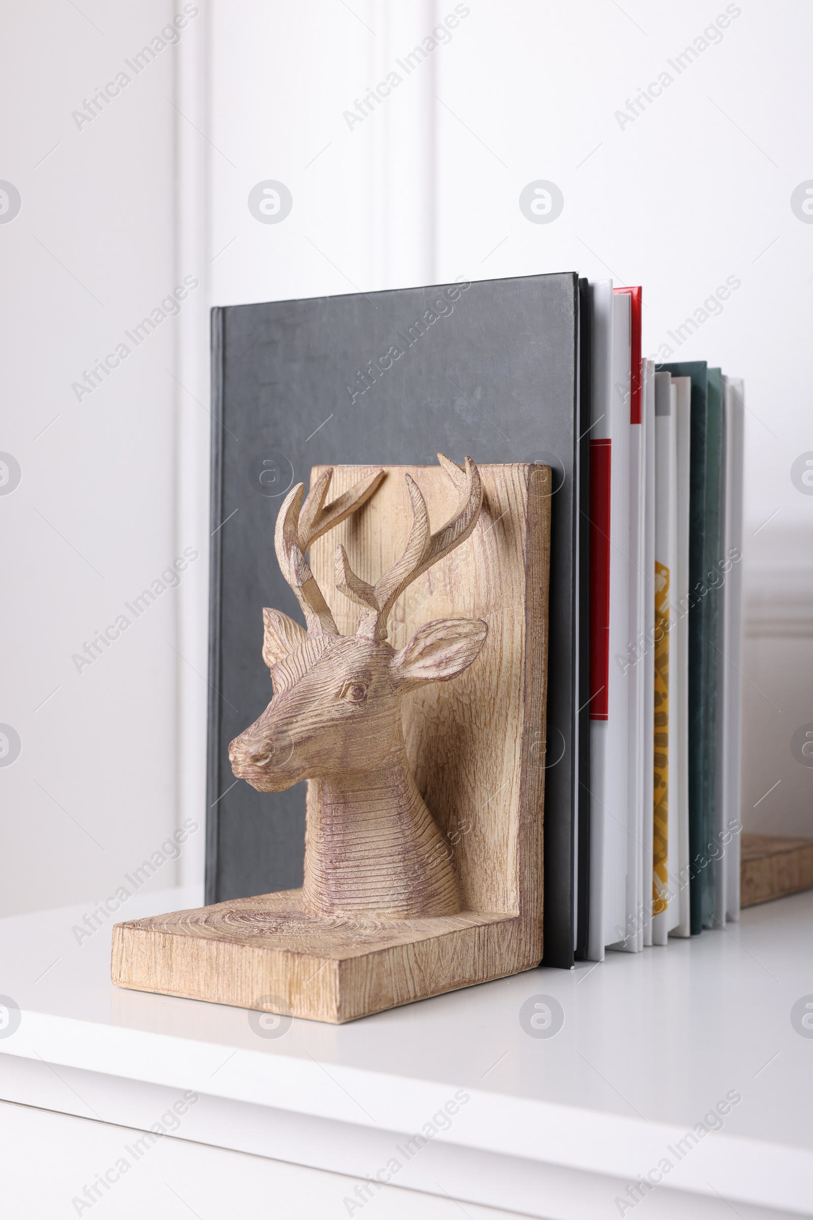 Photo of Wooden deer shaped bookend with books on table indoors