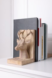 Wooden deer shaped bookend with books on table indoors