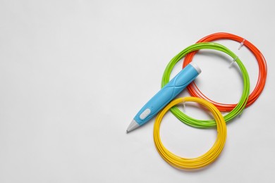 Photo of Stylish 3D pen and colorful plastic filaments on white background, flat lay, Space for text