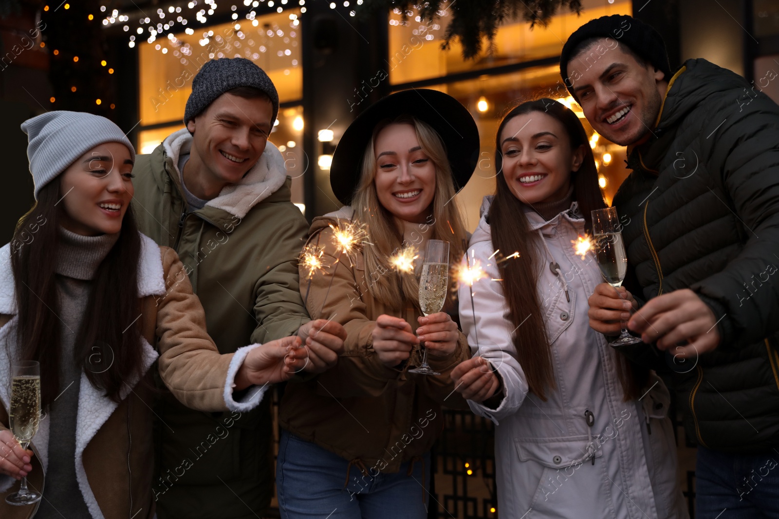 Photo of Group of happy friends with sparklers and champagne at winter fair