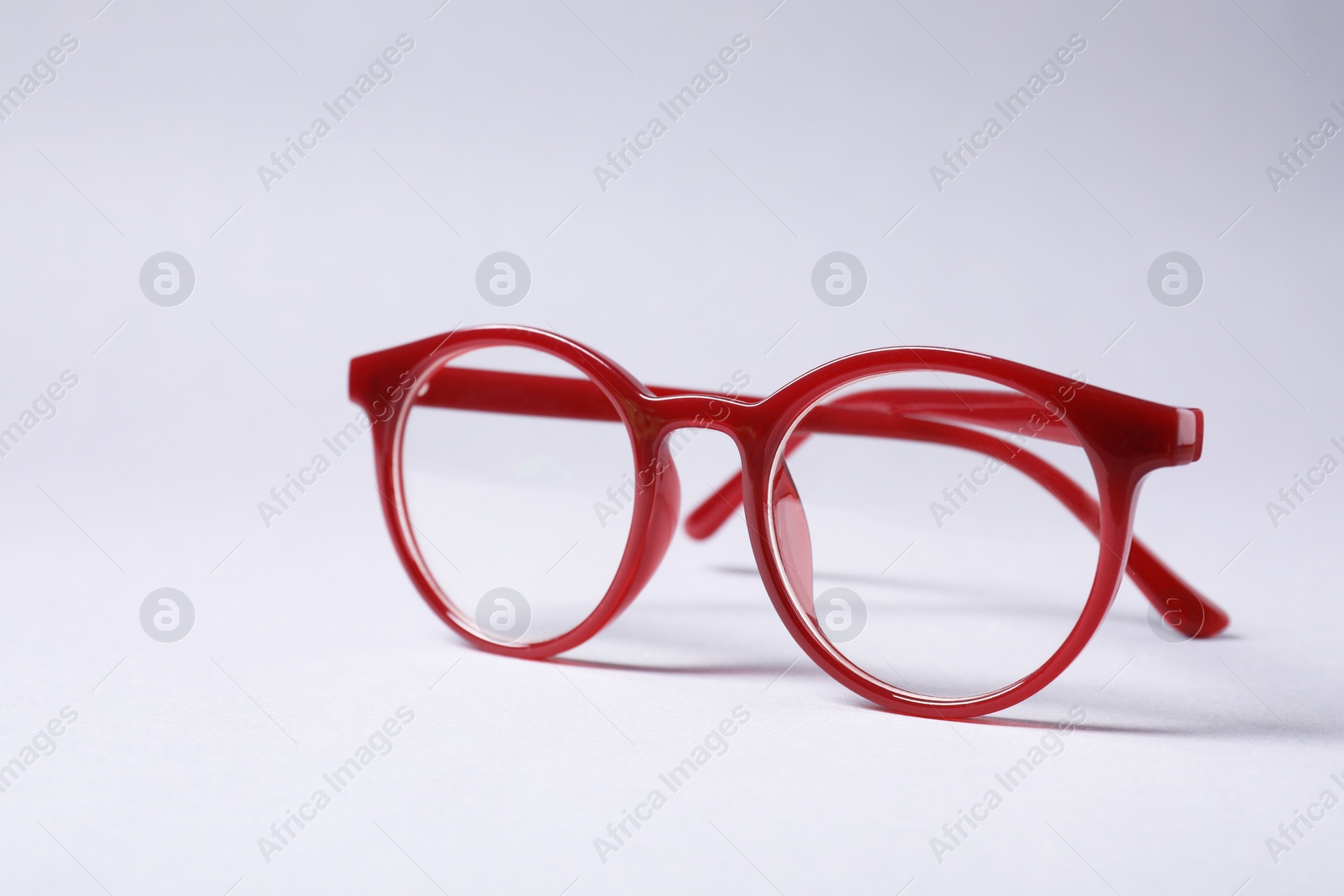 Photo of Stylish pair of glasses with red frame on grey background, space for text