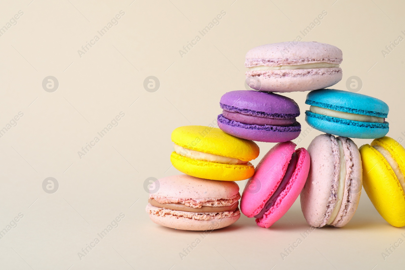 Photo of Delicious colorful macarons on beige background. Space for text