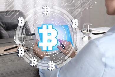 Fintech concept. Scheme with bitcoin symbols and woman using tablet at desk