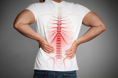 Man suffering from pain in back on light grey background, closeup 