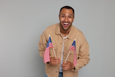 4th of July - Independence Day of USA. Happy man with American flags on light grey background