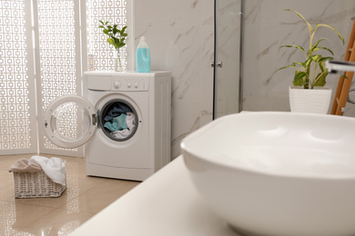 Modern washing machine with towels in bathroom