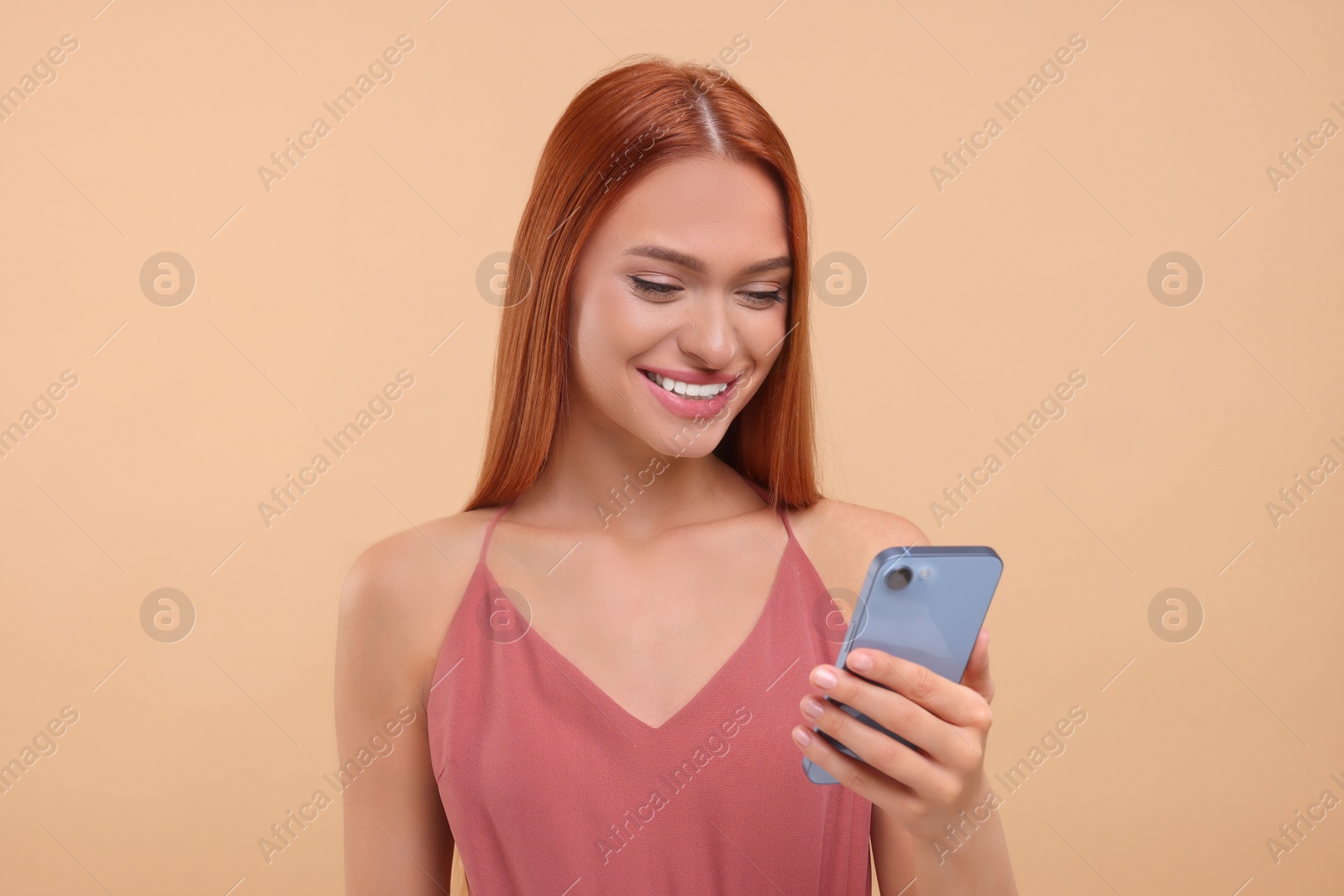 Photo of Beautiful happy woman using smartphone on beige background