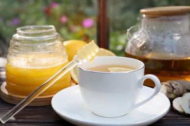 Photo of Cup of delicious tea with lemon and honey on wooden table, closeup