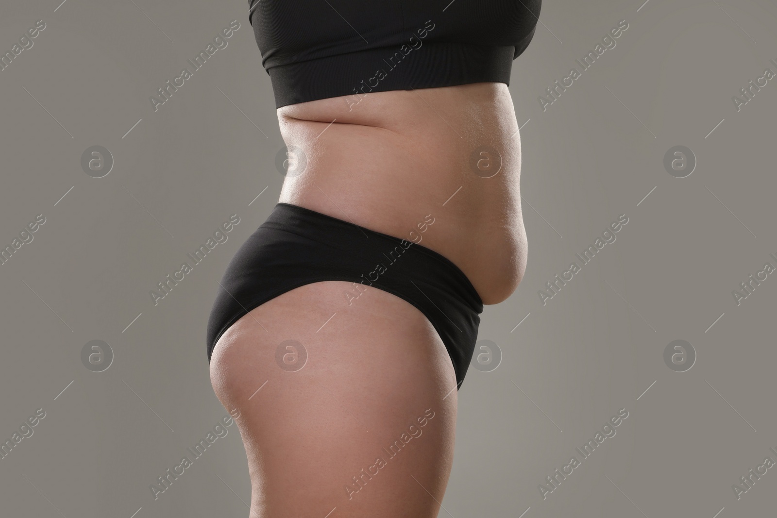 Photo of Woman with excessive belly fat on grey background, closeup. Overweight problem