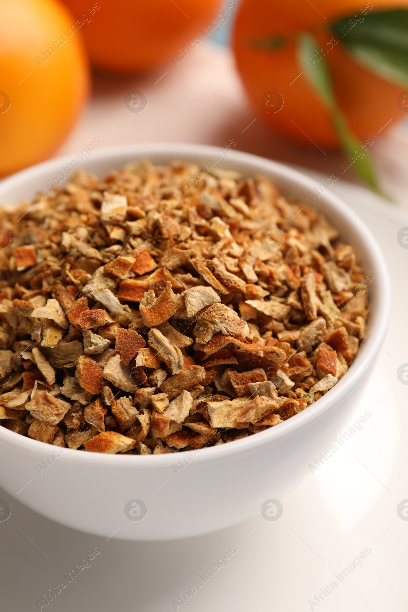Photo of Bowl of dried orange zest seasoning and fresh fruits on plate, closeup