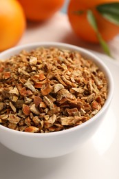 Bowl of dried orange zest seasoning and fresh fruits on plate, closeup