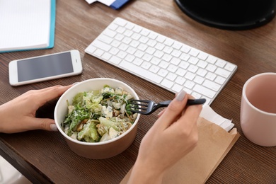 Photo of Office employee having salad for lunch at workplace, closeup. Food delivery