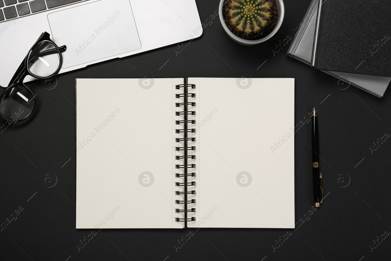 Photo of Flat lay composition with notebook and laptop on black table