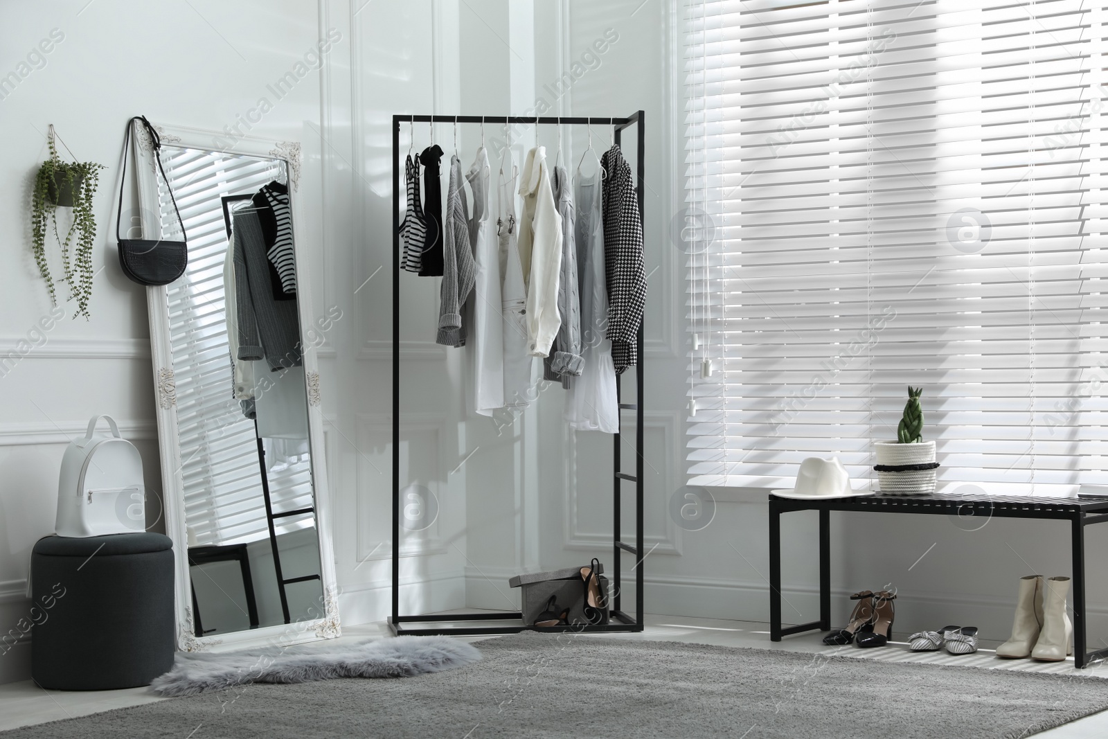 Photo of Rack with stylish women's clothes and large mirror in dressing room. Interior design