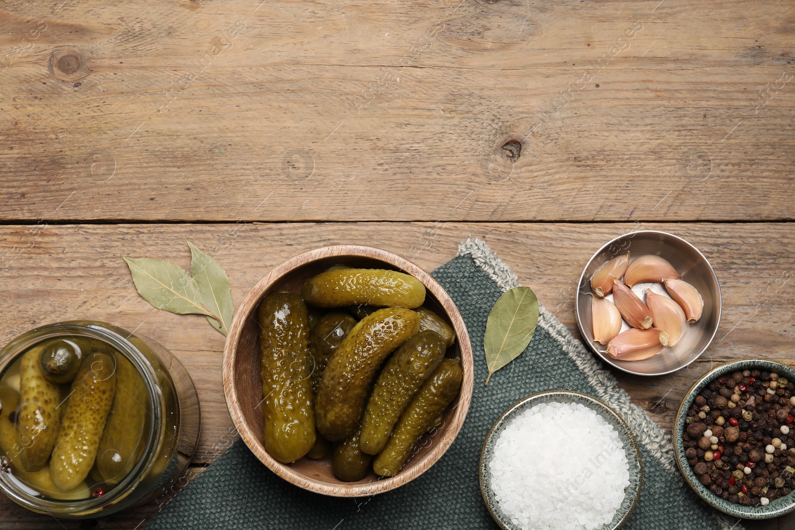 Photo of Tasty pickled cucumbers and spices on wooden table, flat lay. Space for text