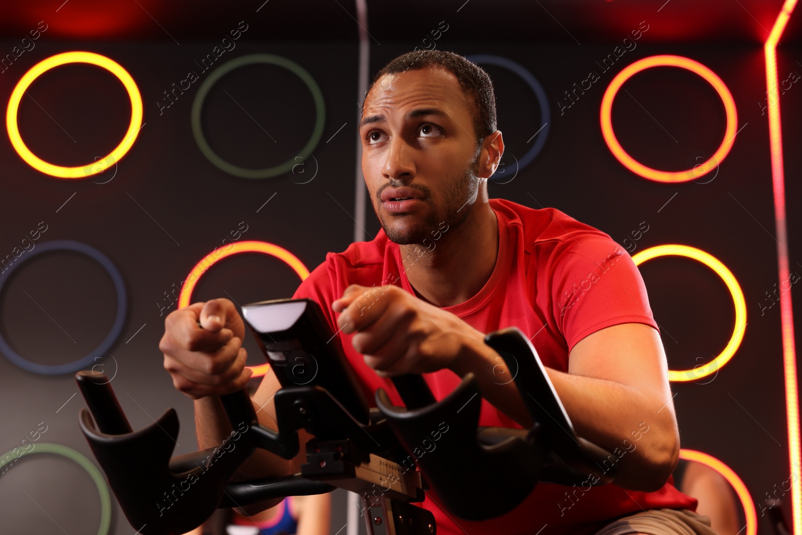 Photo of Young man training on exercise bike in fitness club