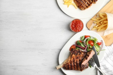 Image of Grilled steak served on white wooden table, flat lay. Space for text