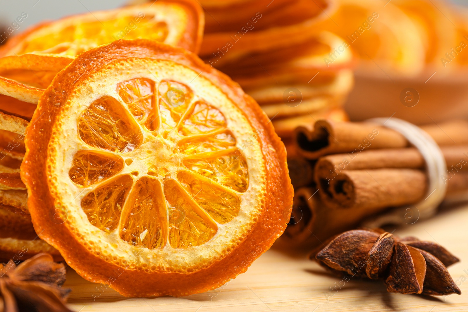 Photo of Dry orange slices, anise stars and cinnamon sticks on wooden board, closeup