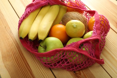 Photo of Net bag with fruits on wooden table