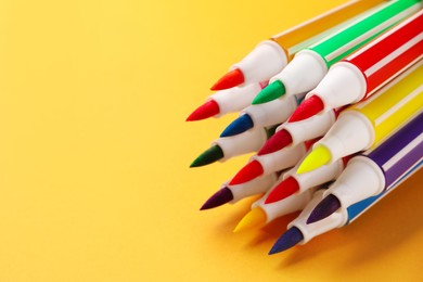 Photo of Many bright markers on yellow background, closeup. Space for text
