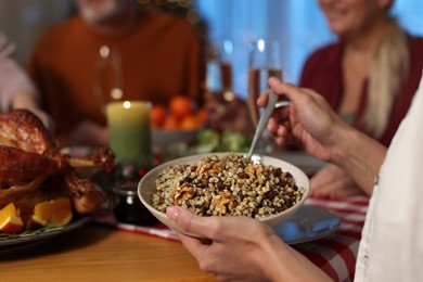 Photo of Woman with bowl of traditional Christmas Slavic dish kutia and her family at festive dinner