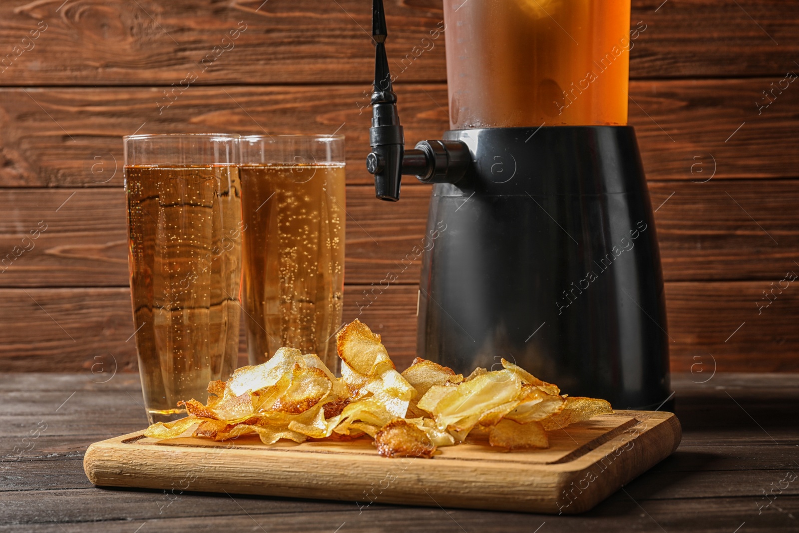 Photo of Beer and wooden board with crispy potato chips on table