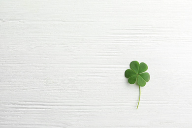 Photo of Clover leaf on white wooden table, top view with space for text. St. Patrick's Day symbol