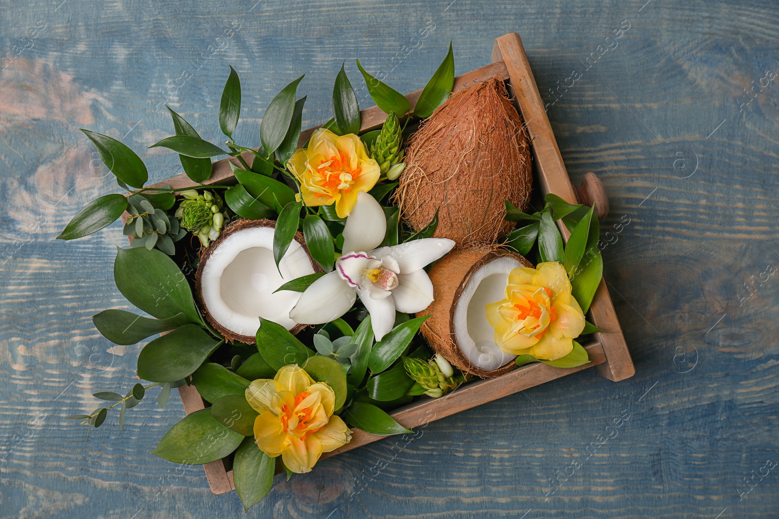 Photo of Box with coconuts and flowers on wooden background