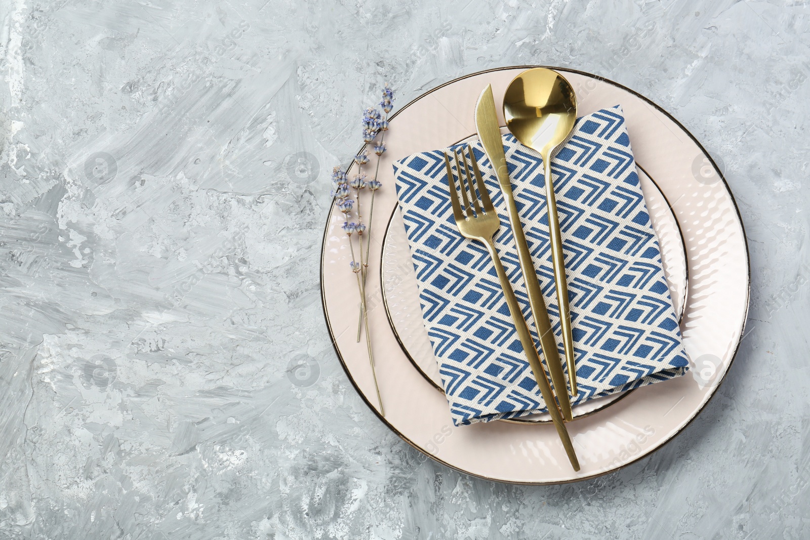 Photo of Clean plates, cutlery, napkin and lavender flowers on light grey textured table, top view. Space for text