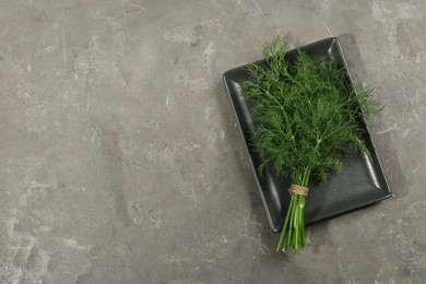 Photo of Bunch of fresh dill on grey table, top view. Space for text