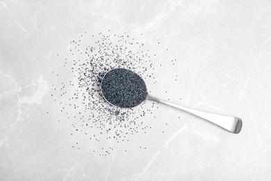 Photo of Spoon with poppy seeds on marble background, top view