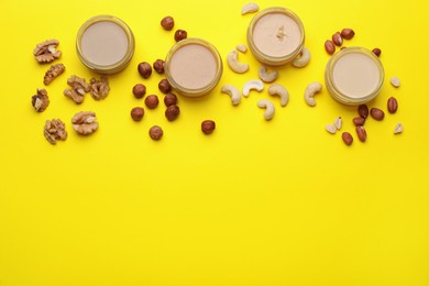 Different types of nut butter and ingredients on yellow background, flat lay. Space for text