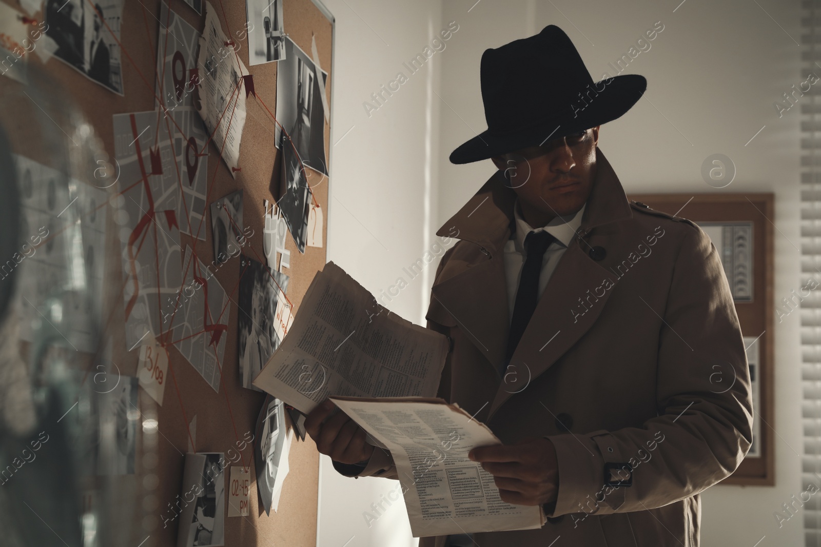 Photo of Detective with newspaper near evidence board in office