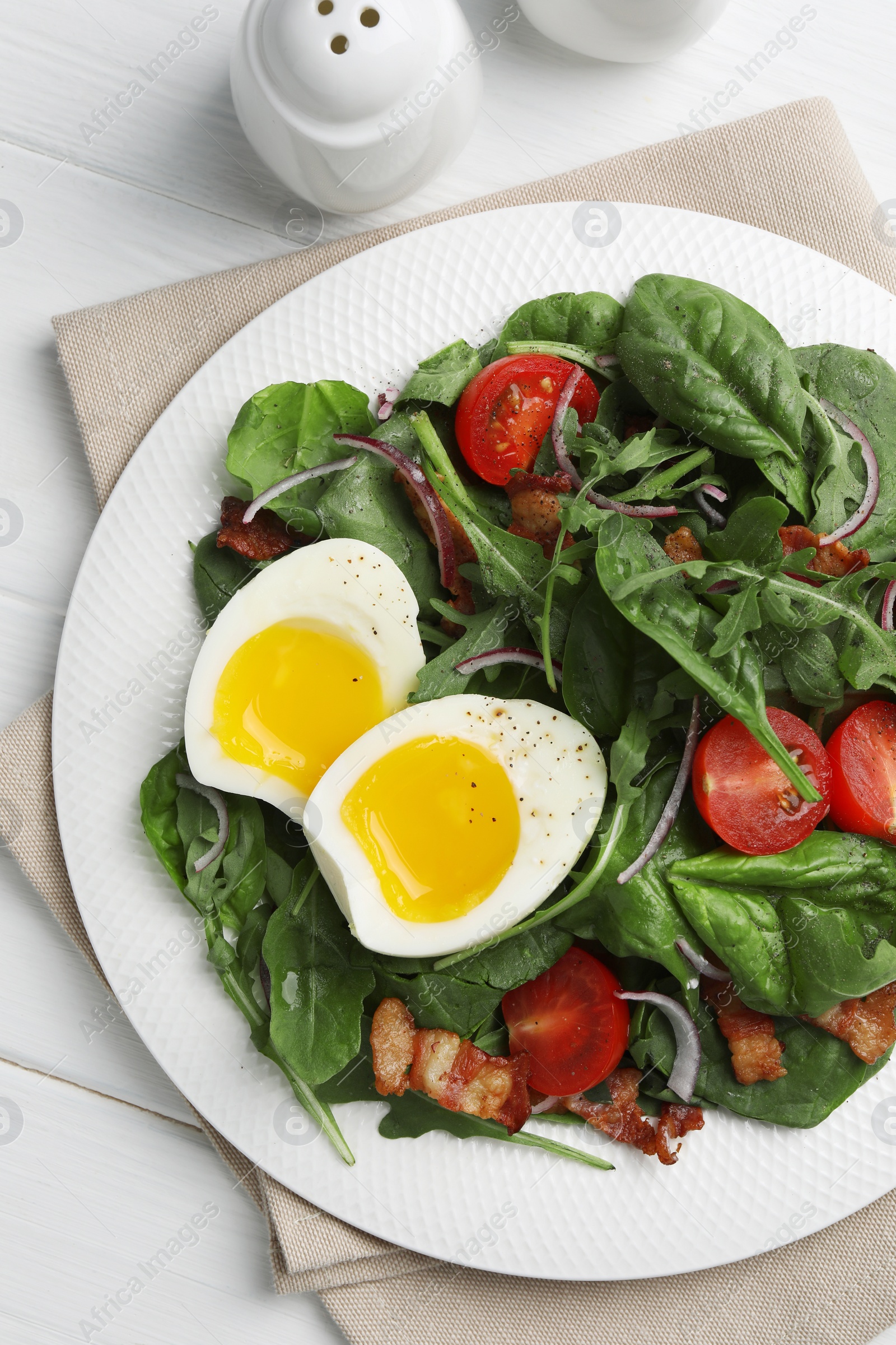 Photo of Delicious salad with boiled egg, bacon and tomatoes served on white wooden table, flat lay