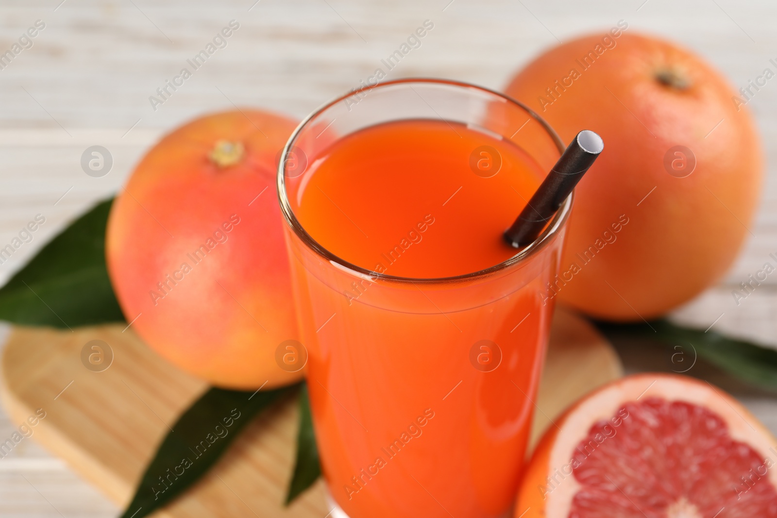 Photo of Tasty grapefruit juice in glass and fresh fruits on table, closeup