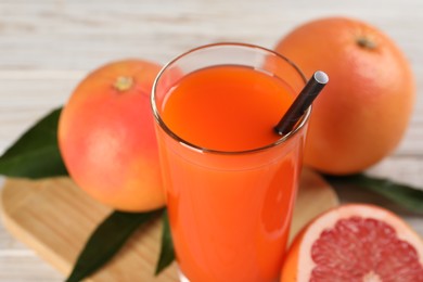 Photo of Tasty grapefruit juice in glass and fresh fruits on table, closeup