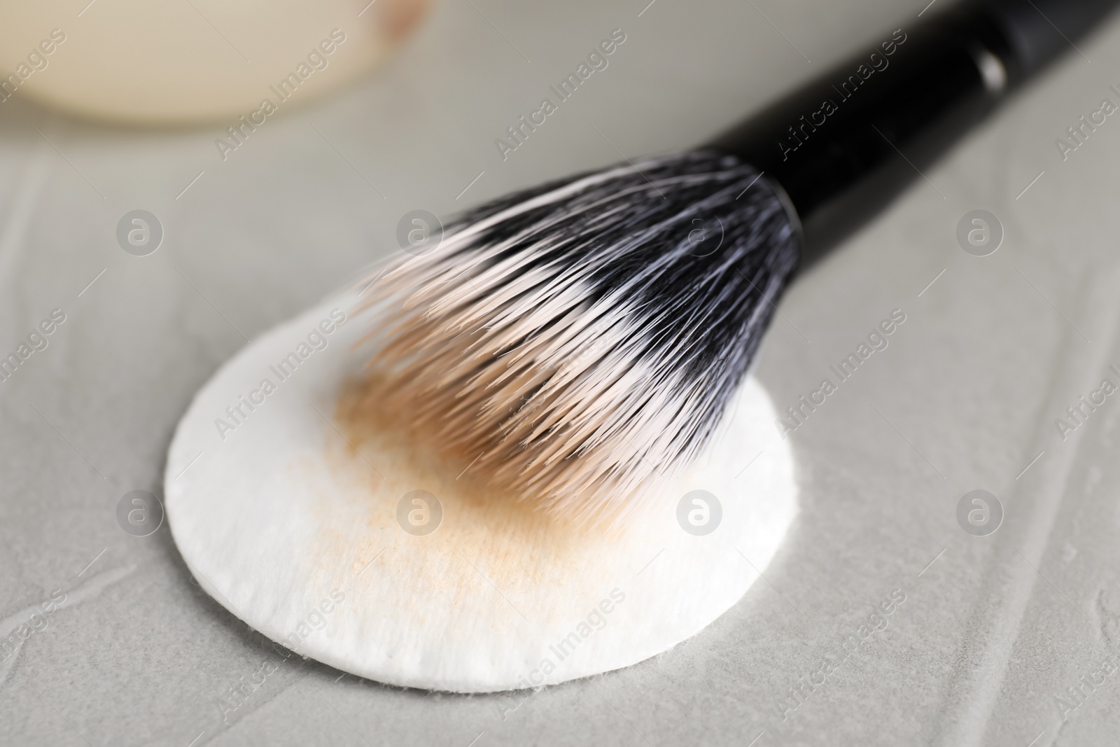 Photo of Cleaning makeup brush on grey table, closeup