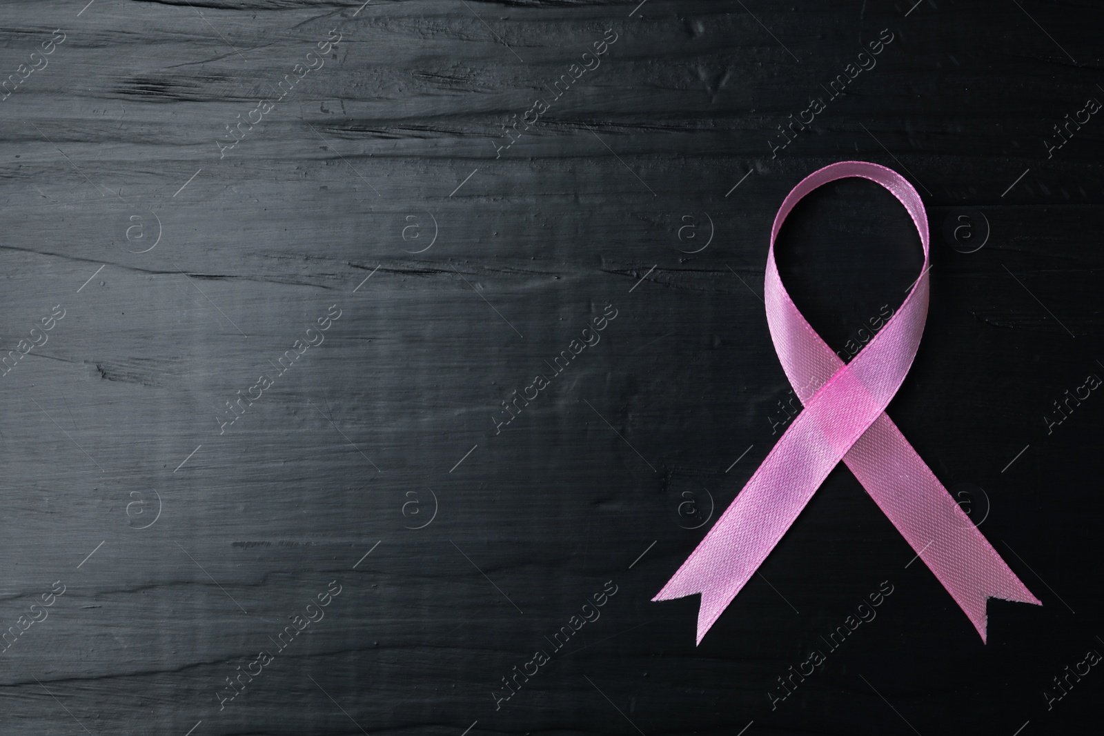 Photo of Pink ribbon on wooden background, top view with space for text. Breast cancer concept