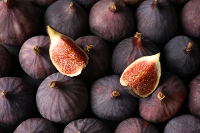 Photo of Tasty cut fig on whole ripe fruits, closeup