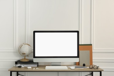 Photo of Stylish workspace with computer and stationery on wooden desk near white wall